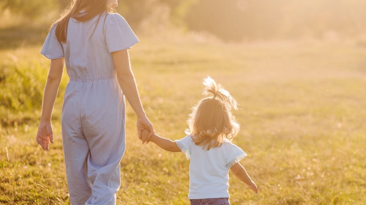 Родител и дете вървят заедно, хванати за ръце